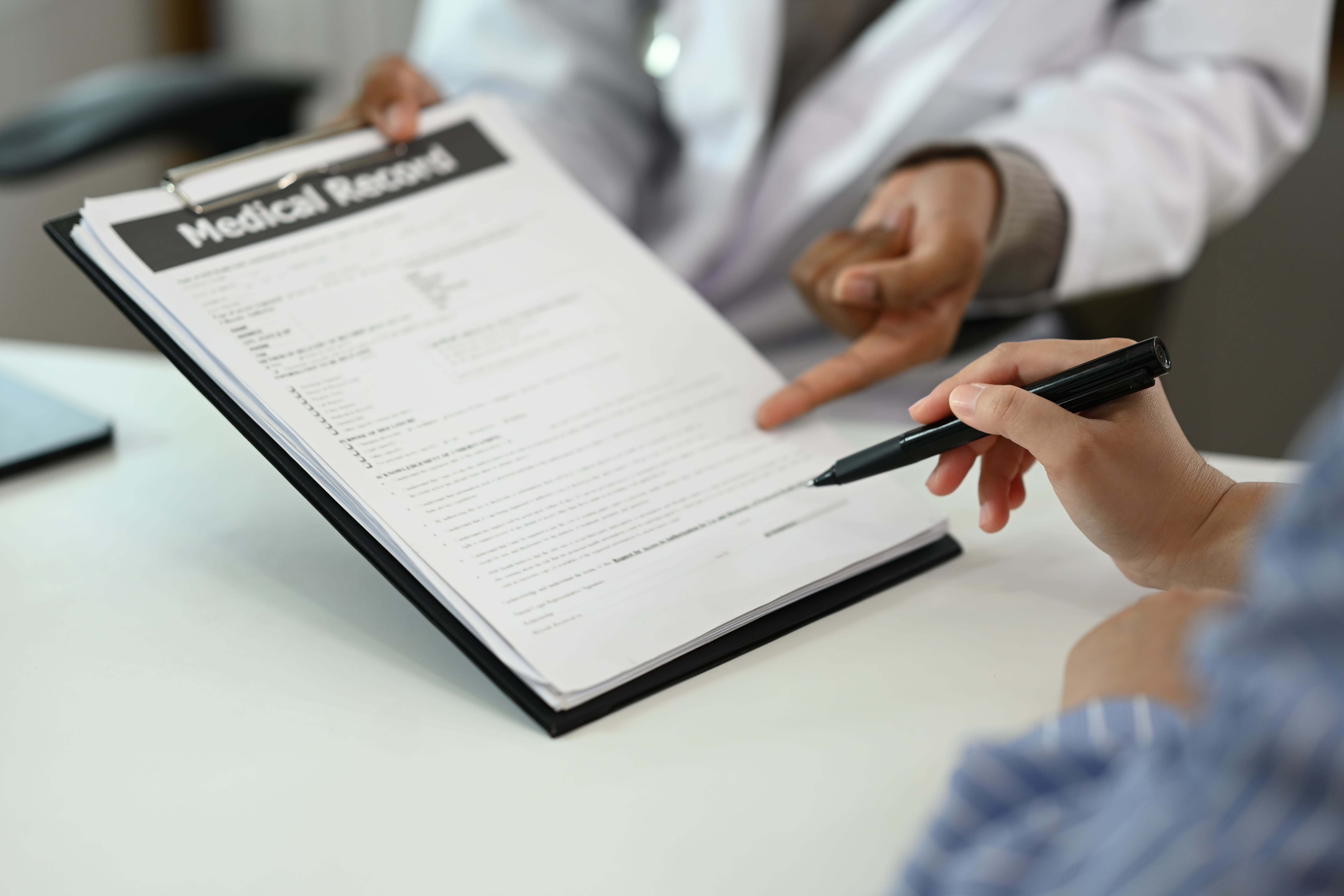 Close up patient filling medical document or signing medical treatment contract.