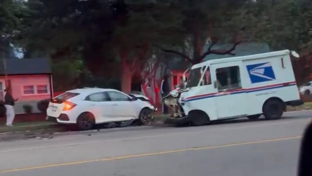 USPS mail truck and white hatchback with front-end damage after a federal vehicle crash on a residential street